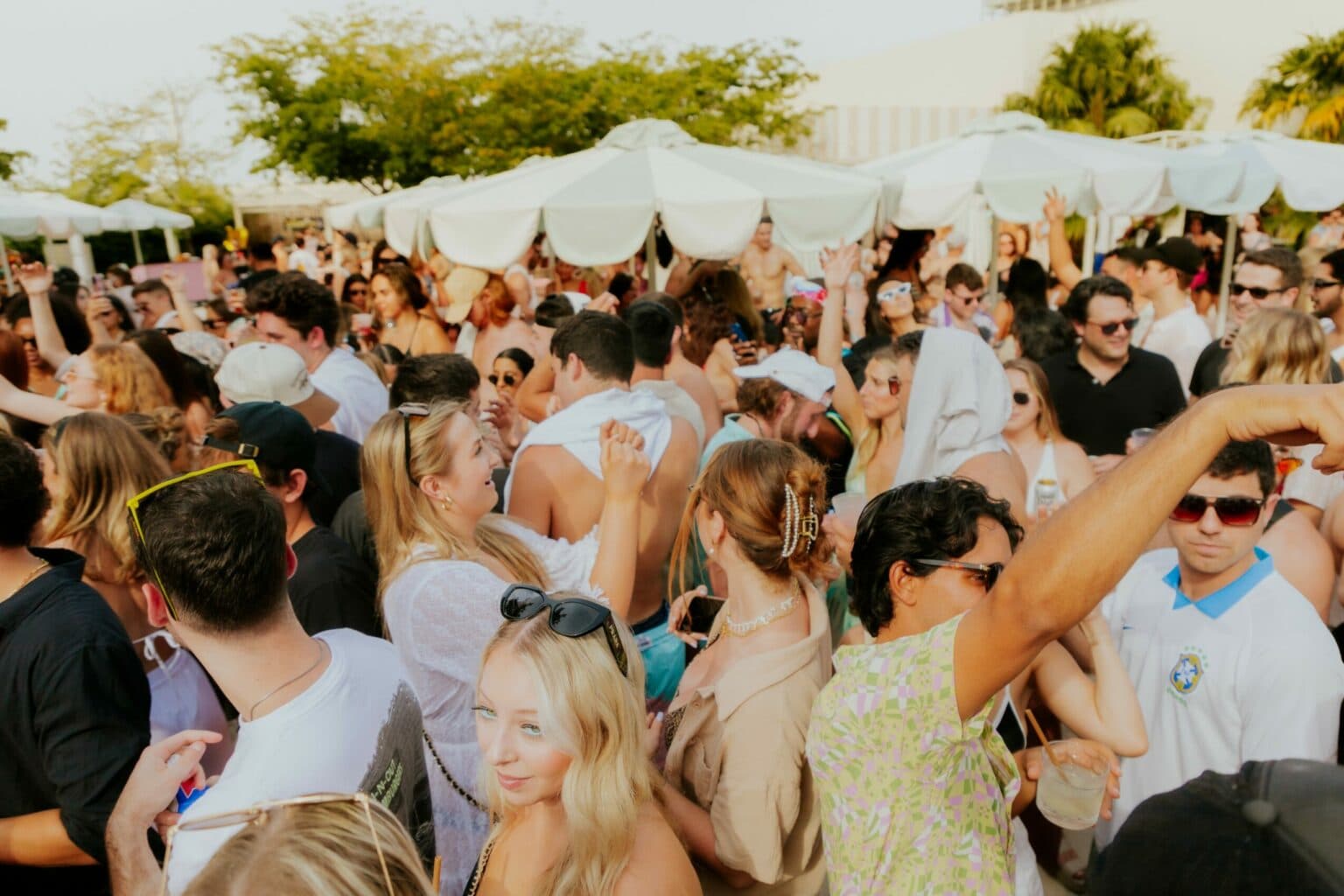 A First Reef day party — a crowd under white umbrellas on a South Florida pool deck